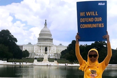 Rowanne Mustafa poses with "We will defend our communities" ACLU poster outside of the U.S. Capitol Building