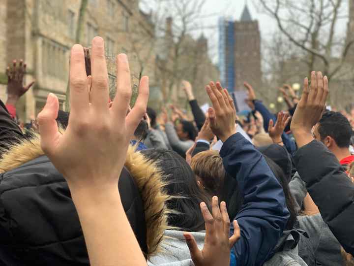 Photo of people with hands raised. 