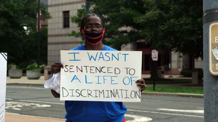 ACLU-CT Smart Justice leader stands with sign: I wasn't sentenced to a life of discrimination