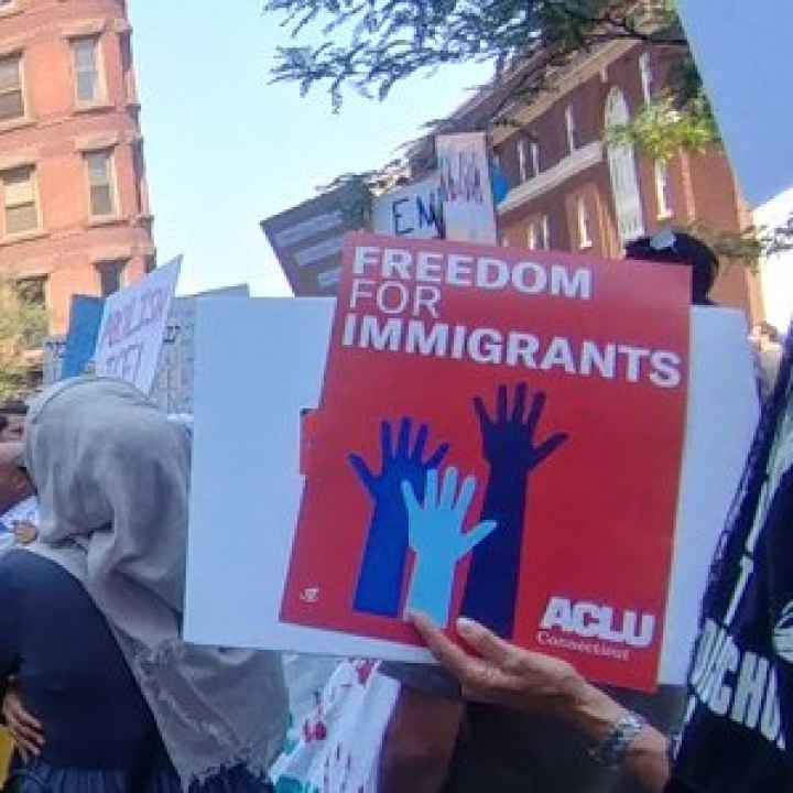 Photo of crowd at Hartford rally, including red ACLU of Connecticut sign that says "freedom for immigrants"