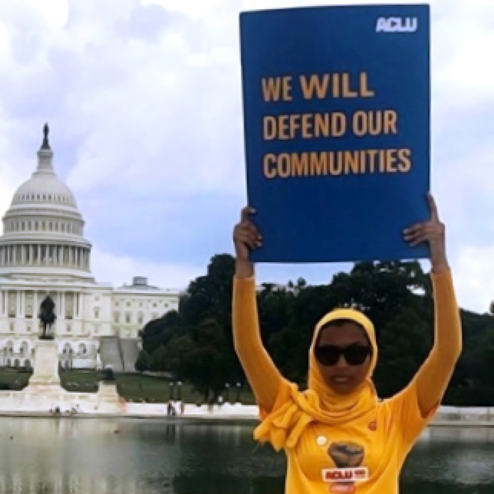 Rowanne Mustafa poses with "We will defend our communities" ACLU poster outside of the U.S. Capitol Building
