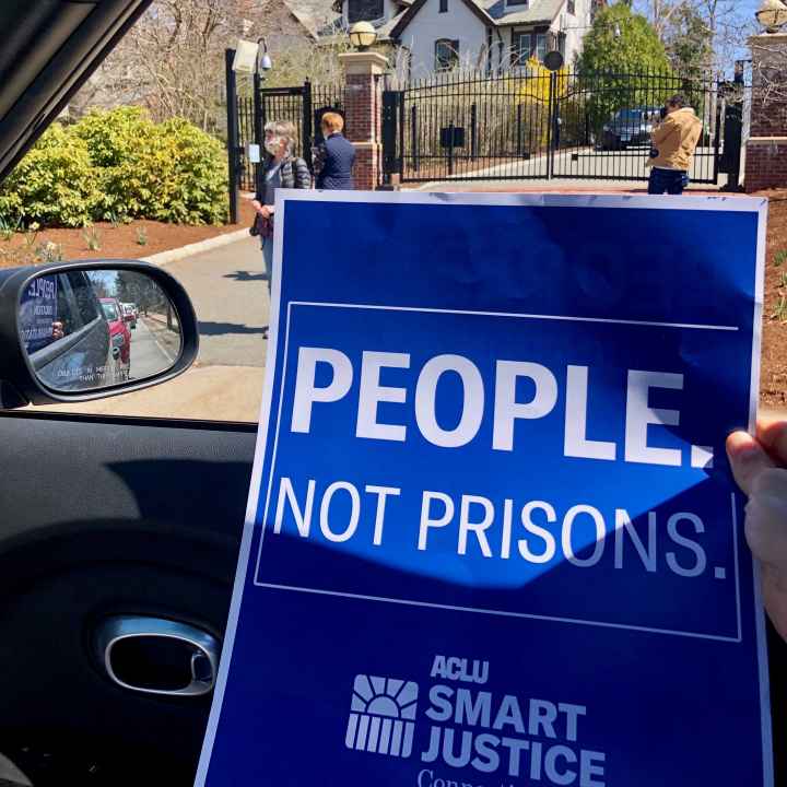 blue aclu of connecticut people not prisons poster in front of Connecticut governor's mansion